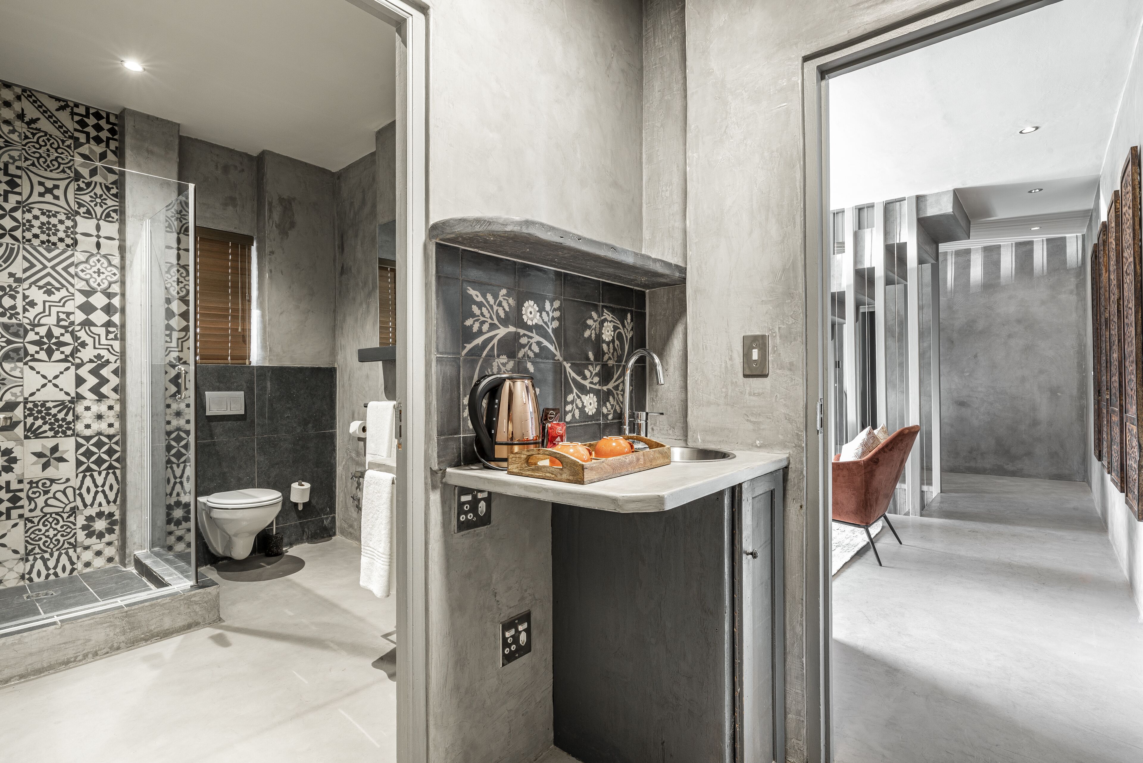 A modern bathroom with a shower, toilet, and a small sink area with a kettle and fruit.