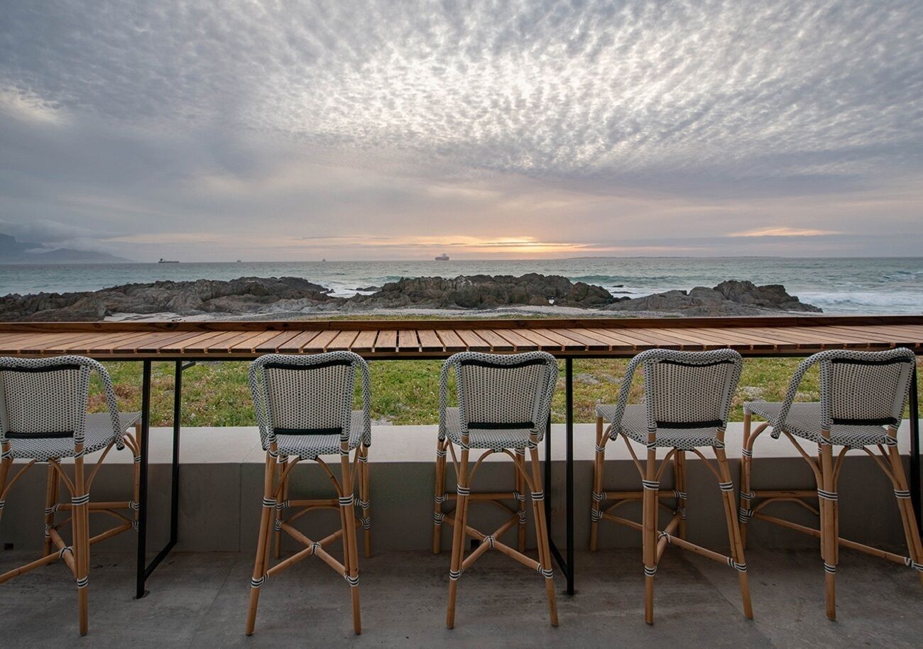 A terrace with wicker chairs and a wooden table overlooking the sea.