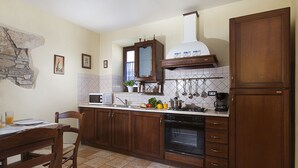 Una cocina con armarios de madera, horno empotrado, microondas y estufa.