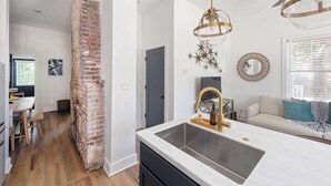 A modern kitchen with a brick accent wall, a white countertop, and a gold faucet.