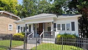 A two-story house with a front porch, a small front yard, and a metal fence.