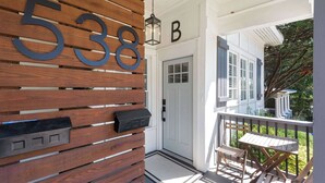 A wooden number display with '538' and a mailbox, a white door, and a porch with a table and chairs.