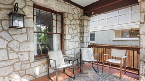 A stone-walled patio with three chairs and a table, a lantern, and a window with a view of greenery. - Edgy Overlook (Atlanta)