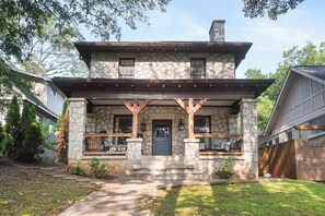 A two-story stone house with a stone chimney, a front porch with wooden railings, and a number '604' on the front. - Edgy Overlook (Atlanta)