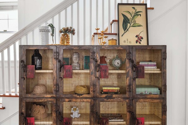 A staircase with a rustic wooden crate display containing various items like hats, books, and decorative objects.