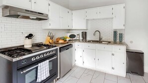 A modern kitchen with white cabinets, a stainless steel stove, a dishwasher, and a microwave. - Edgy Overlook (Atlanta)