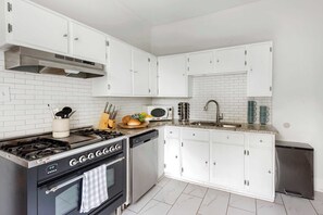A modern kitchen with white cabinets, a stainless steel stove, a dishwasher, and a microwave.