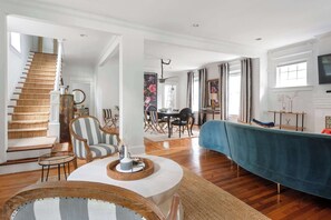 A spacious living room with a staircase, a dining area, and a TV mounted on the wall. - Edgy Overlook (Atlanta)