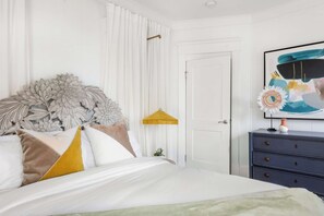 A bedroom with a bed, a nightstand, a dresser, and a door.