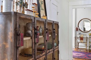 A vintage metal cabinet with multiple compartments, each containing a birdcage.