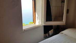 Une chambre avec un lit, une fenêtre donnant sur la mer et un rideau.