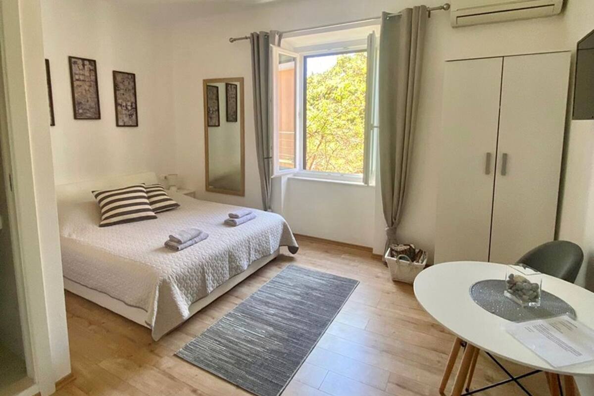 Un dormitorio con cama, escritorio, silla, ventana y una lámpara en el techo.