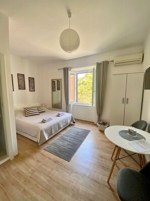 Ett sovrum med en säng, ett skrivbord, en stol, ett fönster och en taklampa.