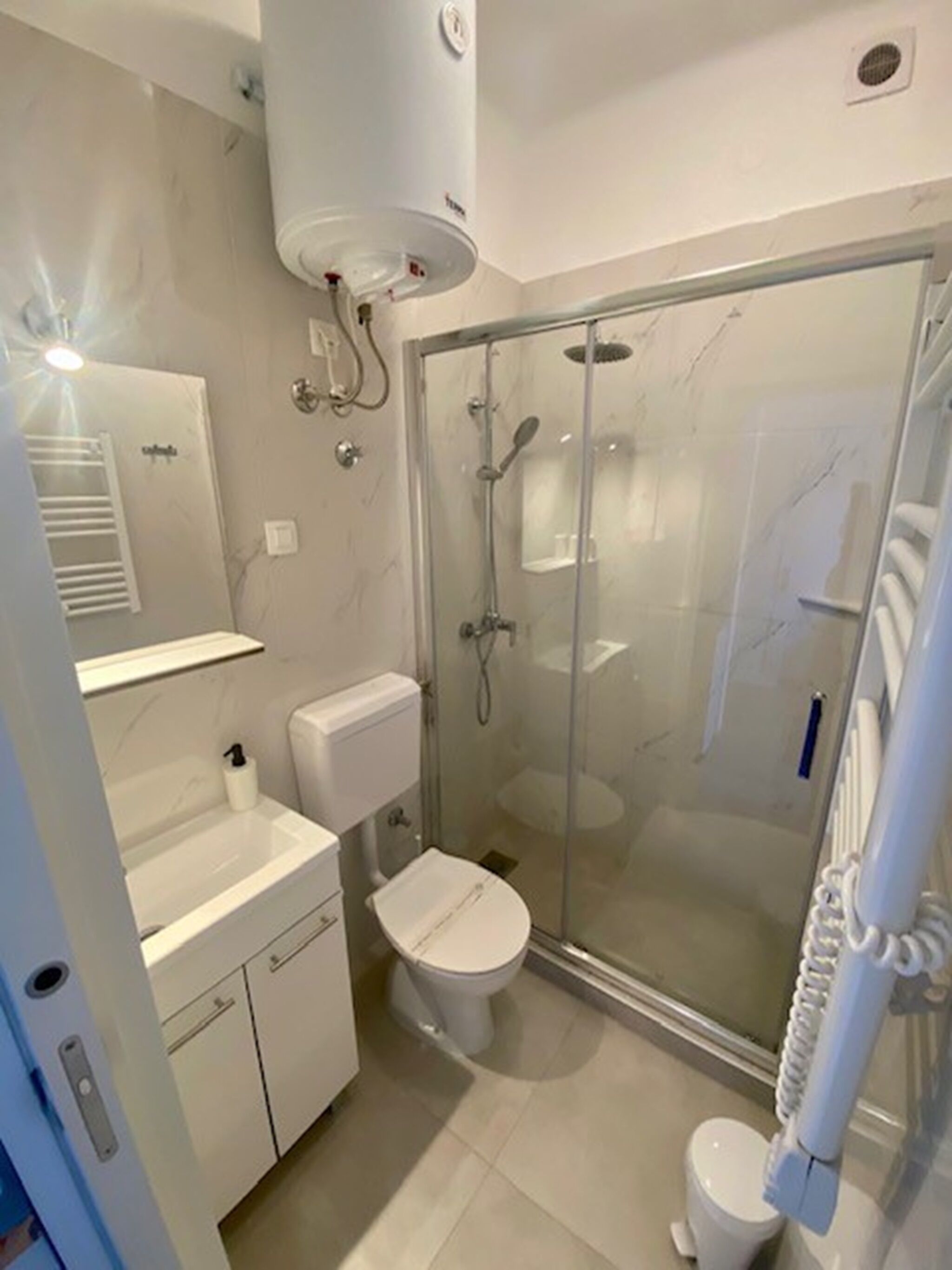 A modern bathroom with a glass-enclosed shower, a toilet, and a sink.