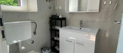 A compact bathroom with a toilet, sink, and mirror.