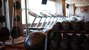 Ett gym med löpband, en stor träningsboll och ett ställ med hantlar.