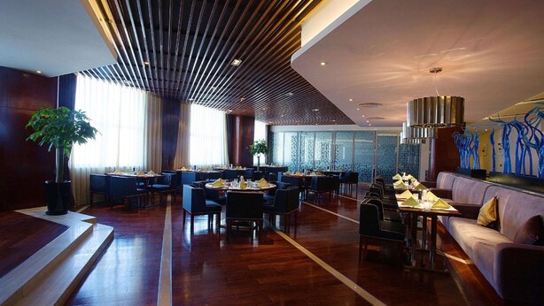 En modern restaurang med trägolv, flera matbord och en variation av sittplatser, inklusive stolar och soffor.