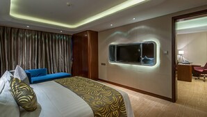 Ett modernt hotellrum med en stor säng, en blå soffa, ett fönster med utsikt och ett skrivbord med en lampa.