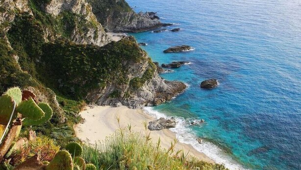A coastal landscape with rocky cliffs, clear blue waters, and a sandy beach. - Casa Lampedusa, for 2 people, with sea view, shared pool and access to the beach (Capo Vaticano Ricadi)
