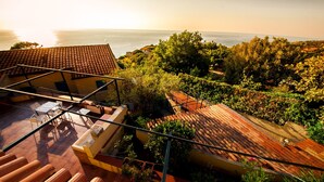 A rooftop terrace with a view of the sea, surrounded by lush greenery and terracotta-tiled roofs. - Casa Lampedusa, for 2 people, with sea view, shared pool and access to the beach (Capo Vaticano Ricadi)