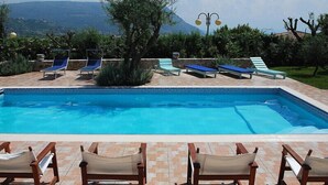 Ein Pool mit Liegestühlen und Blick auf Berge.