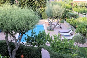 A pool area with lounge chairs and a stone wall.