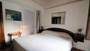 Ein Schlafzimmer mit Bett, Nachttisch, Spiegel und einem Bild an der Wand.