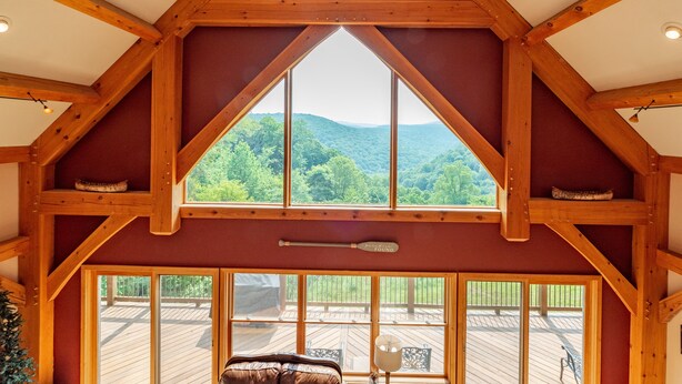 Une pièce dotée d’une grande fenêtre donnant sur une terrasse et des montagnes.