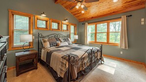 Une chambre à coucher avec un grand lit, un plafond en bois et de nombreuses fenêtres.
