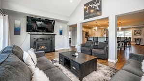 A modern living room with a fireplace, grey sofas, a coffee table, and a television.