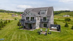 A two-story house with a balcony, a fire pit, and outdoor seating.