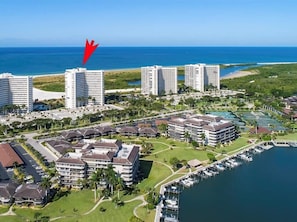 An aerial view of a coastal hotel complex with multiple buildings, a marina, and a beach. - Beachfront 2BR/2BA condo with pool, wifi, and Gulf views. (Marco Island)