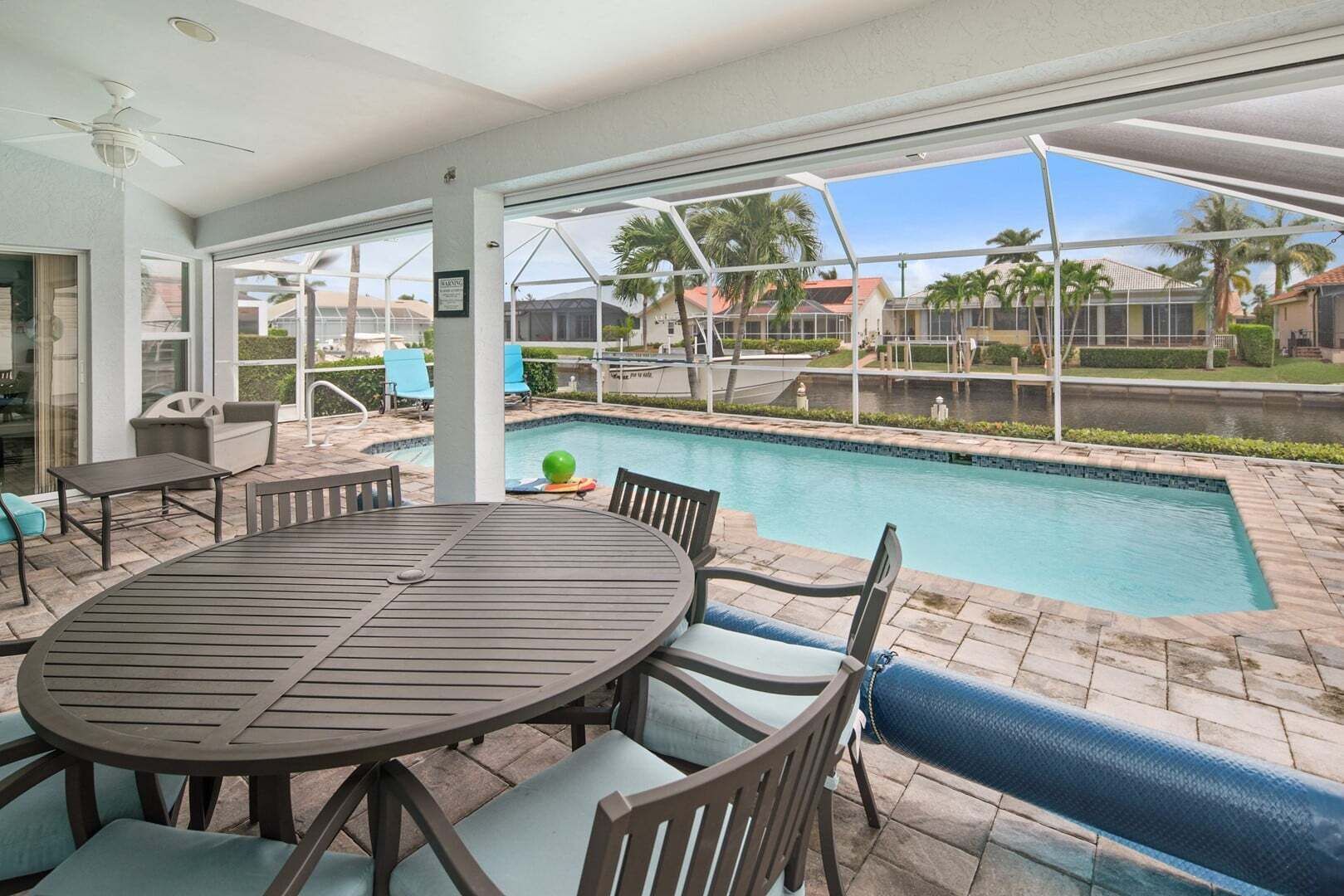 A covered outdoor area with a pool, seating, and a view of the surrounding neighborhood.