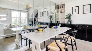 Una cucina moderna con una grande isola, mobili bianchi e un'area da pranzo con tavolo bianco e sedie nere.