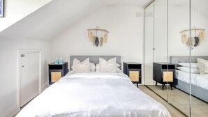Una camera da letto con un letto grande, due comodini con degli altoparlanti, un armadio e uno specchio.