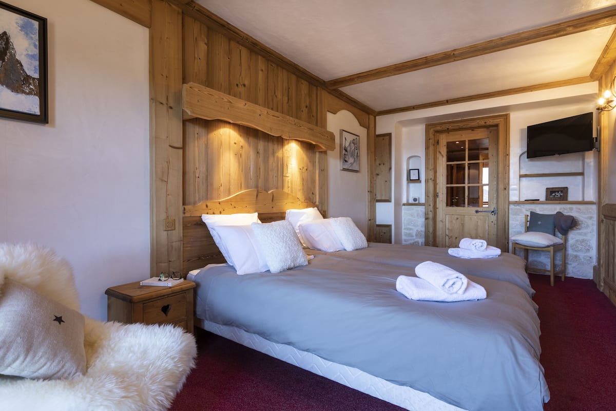 Un dormitorio acogedor con una cama grande, cabecero de madera y un televisor de pantalla plana en la pared.