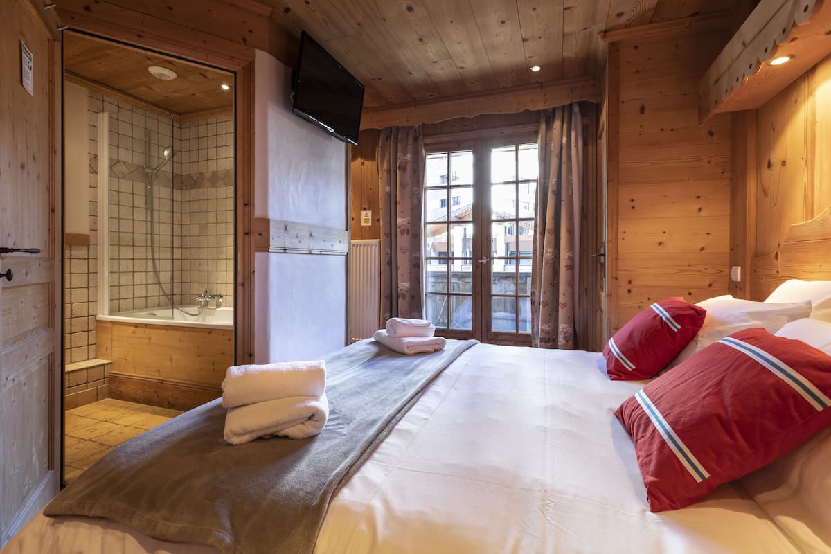 Una habitación de cabaña de madera con cama, ducha y ventana.