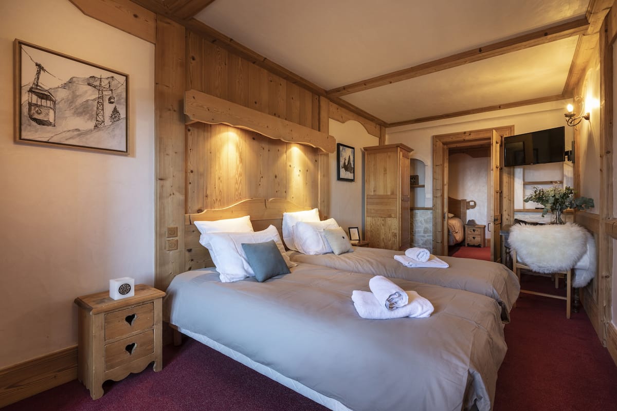 Habitación de hotel con paneles de madera, dos camas con almohadas, una mesita de noche, un cuadro y un espejo.