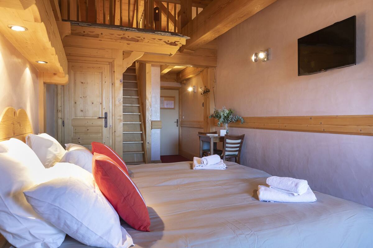 Habitación de hotel con cama, almohadas, televisor, escritorio y silla.