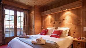 Una habitación de madera con cama, mesita de noche y ventana con cortinas.
