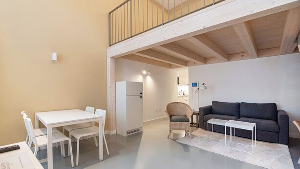 Ett kompakt bostadsutrymme med en matplats, en soffa, en fåtölj och ett litet bord.