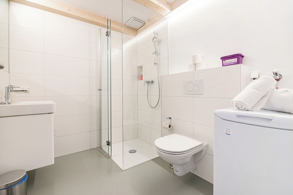 A modern bathroom with a glass-enclosed shower, a toilet, and a sink.