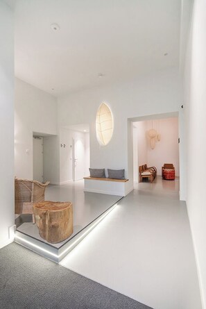 A minimalist interior with a central seating area, a large wooden sculpture, and a unique ceiling light fixture. - Vorgarten Apartments with Aircondition (Vienna)