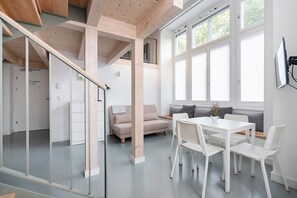A modern interior with a dining area, a sofa, and a staircase.