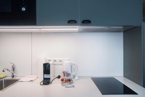 A modern kitchen with a built-in coffee maker, a kettle, and a black induction cooktop.
