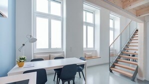 En modern inredning med en trappa, en matplats med stolar och ett bord samt stora fönster.