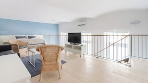 A modern living room with a sofa, chairs, a TV on a stand, and a balcony with a railing. - Vorgarten Apartments with Aircondition (Vienna)