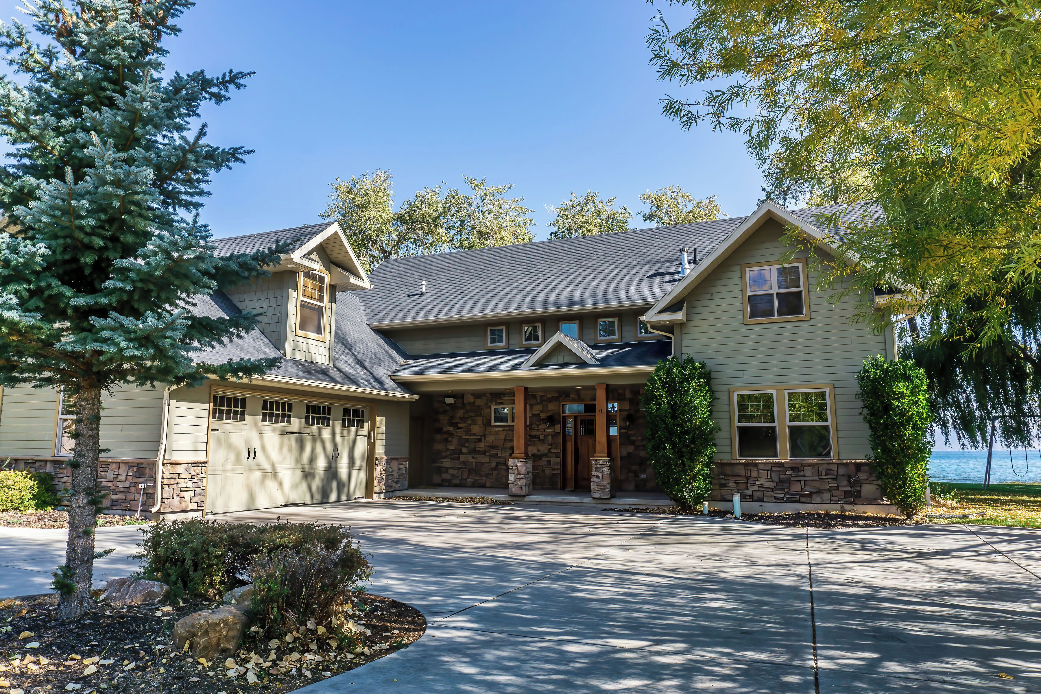 A two-story house with a stone facade, a garage, and a driveway leading to the entrance.