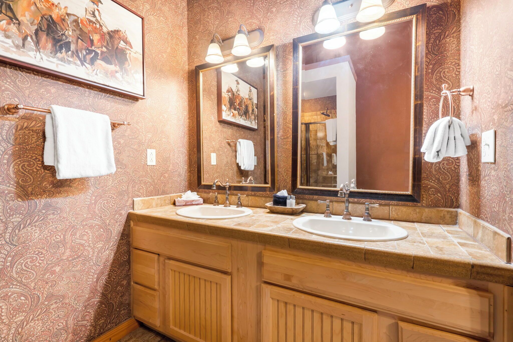 A bathroom with two sinks, wooden cabinets, and a large mirror.