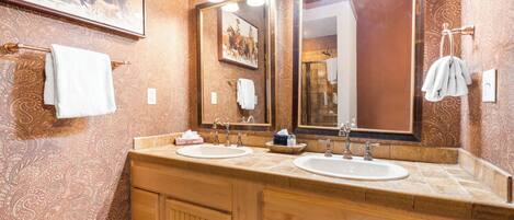 A bathroom with two sinks, wooden cabinets, and a large mirror.